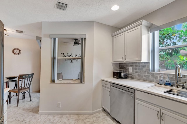 kitchen with visible vents, a sink, stainless steel dishwasher, light countertops, and decorative backsplash