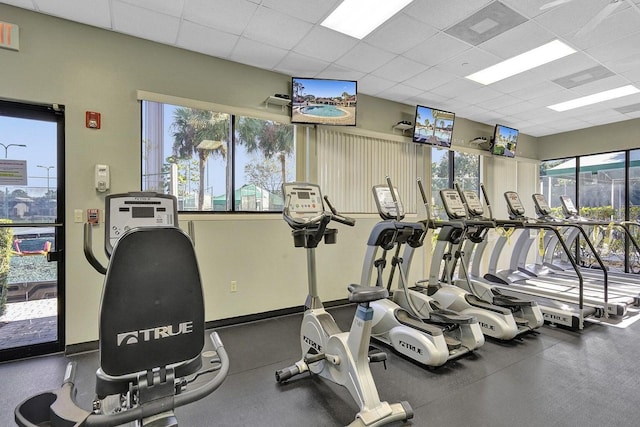 workout area featuring a paneled ceiling and baseboards