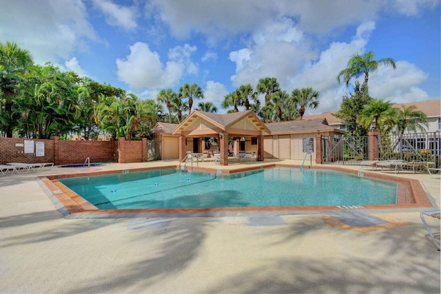 pool with a patio area and fence