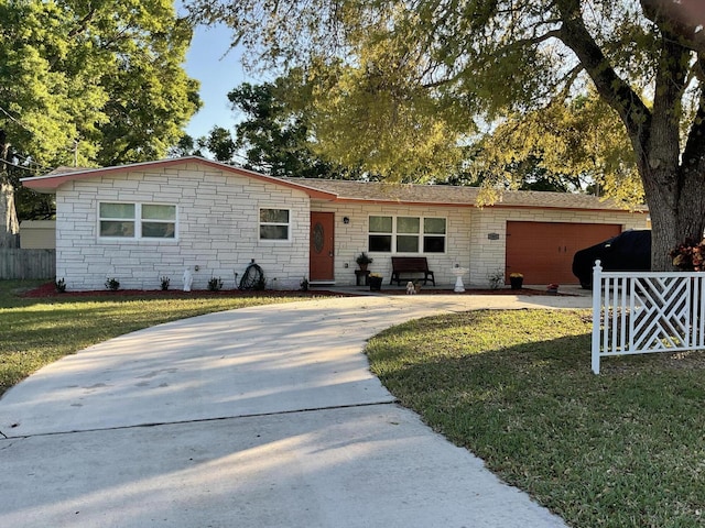 ranch-style house with stone siding, fence, concrete driveway, an attached garage, and a front yard