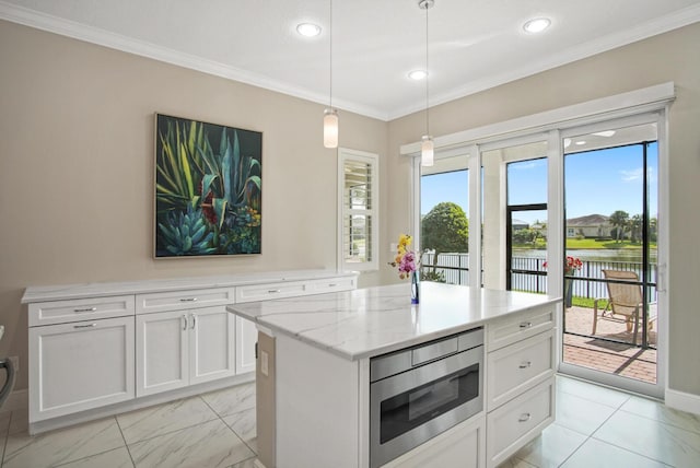 kitchen featuring light stone countertops, crown molding, white cabinetry, stainless steel microwave, and a center island