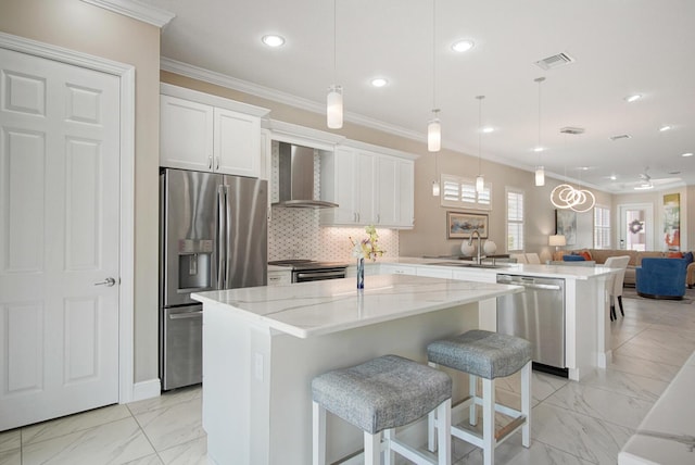 kitchen featuring marble finish floor, appliances with stainless steel finishes, a peninsula, and wall chimney range hood