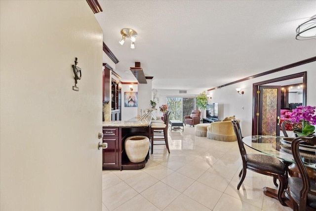 dining area with light tile patterned floors and crown molding