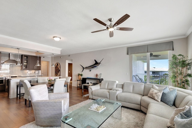 living area with ceiling fan, dark wood finished floors, and ornamental molding