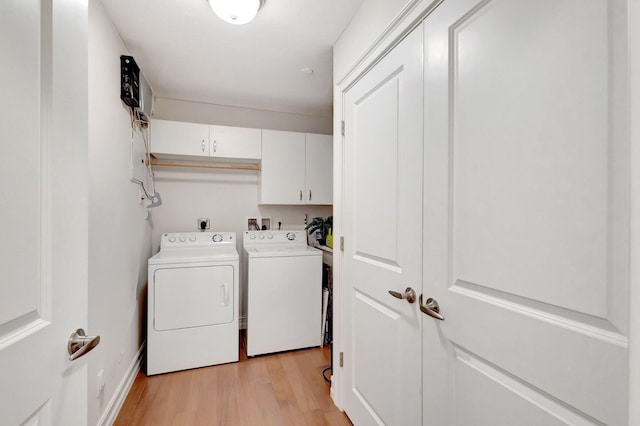 clothes washing area with washing machine and clothes dryer, cabinet space, and light wood-style floors