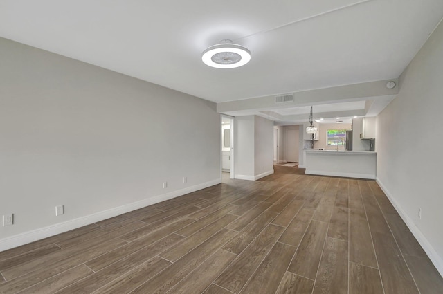 unfurnished living room with visible vents, baseboards, and dark wood-type flooring