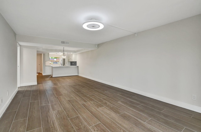 unfurnished living room with visible vents, baseboards, and dark wood-style floors