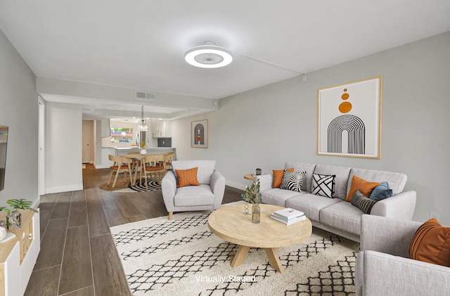 living area featuring baseboards, visible vents, and dark wood-style flooring