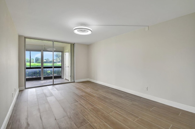 spare room featuring floor to ceiling windows, wood finished floors, and baseboards
