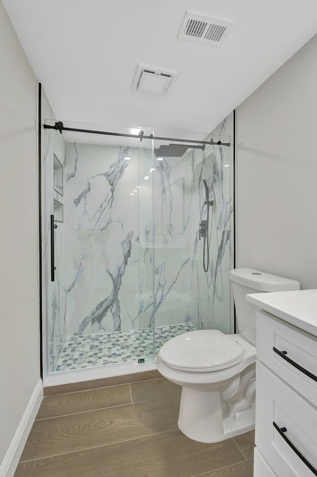 bathroom featuring vanity, wood finished floors, visible vents, a marble finish shower, and toilet
