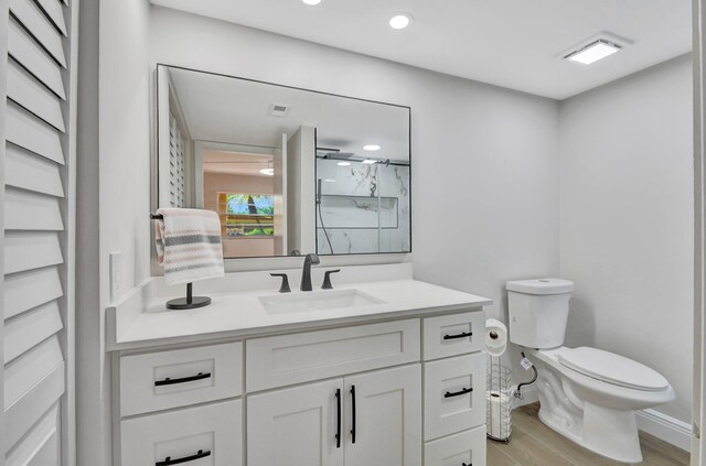 bathroom featuring baseboards, walk in shower, toilet, wood finished floors, and vanity
