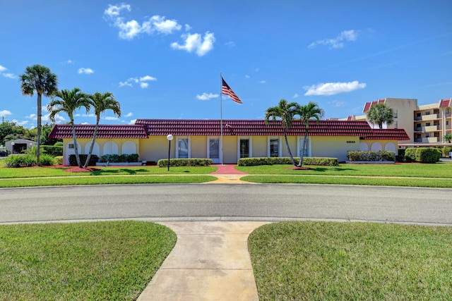 view of front of property with stucco siding, a front lawn, and a tile roof