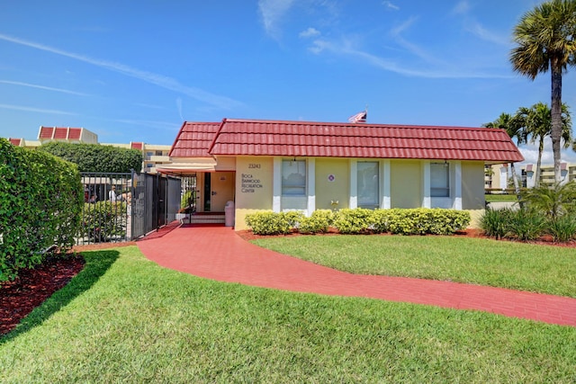 view of front of property with stucco siding, a front lawn, and a tile roof