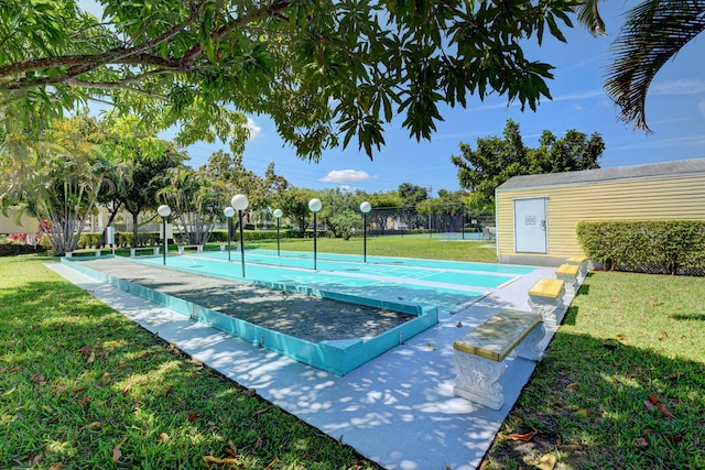 view of property's community featuring fence, a lawn, and shuffleboard