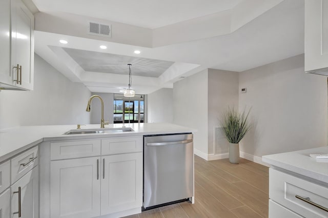 kitchen featuring visible vents, a sink, a peninsula, light countertops, and dishwasher