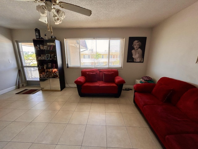 living area featuring light tile patterned floors, baseboards, a textured ceiling, and ceiling fan