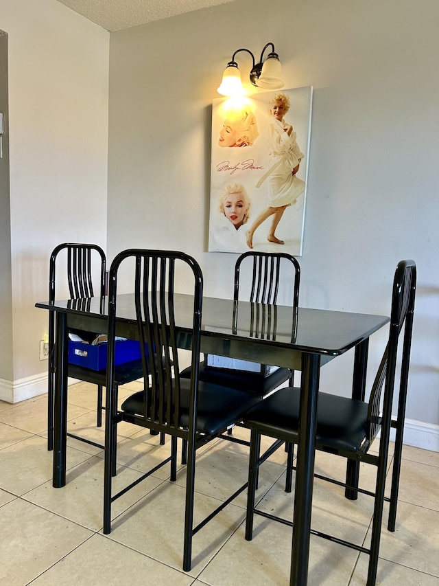 dining room featuring light tile patterned floors, baseboards, and a textured ceiling