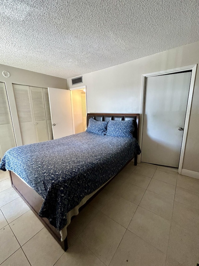 tiled bedroom with visible vents and a textured ceiling