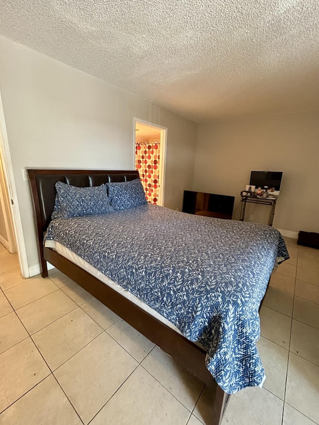 bedroom with tile patterned floors, a textured ceiling, and baseboards