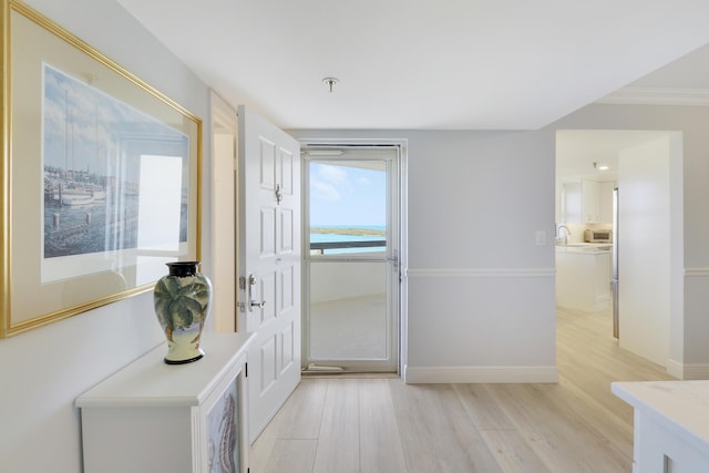 interior space featuring baseboards, light wood-type flooring, and ornamental molding