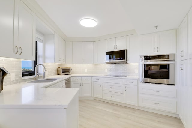 kitchen featuring a sink, decorative backsplash, white cabinetry, and stainless steel appliances