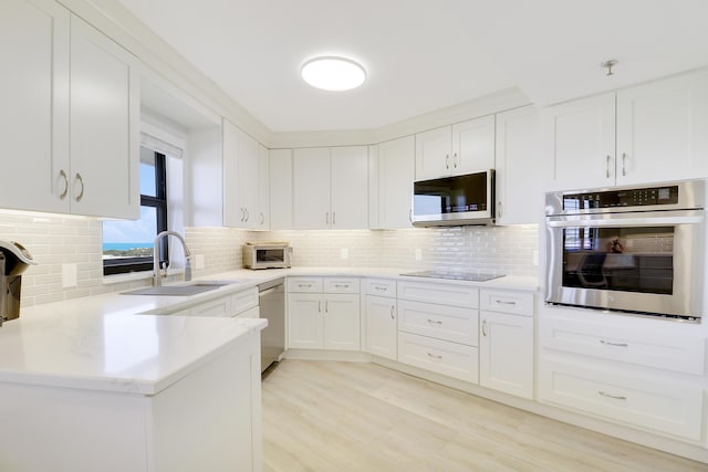 kitchen with a sink, white cabinetry, backsplash, and stainless steel appliances