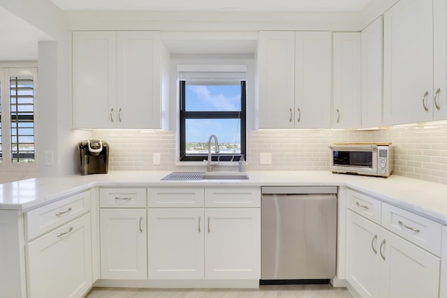 kitchen featuring stainless steel dishwasher, white cabinetry, and a sink