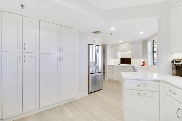 kitchen with light wood-style flooring, visible vents, stainless steel refrigerator with ice dispenser, and white cabinets