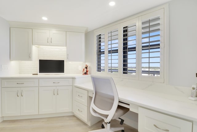 home office with recessed lighting, light wood-type flooring, and built in desk