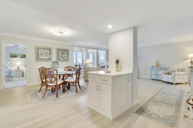 kitchen featuring baseboards, light wood-style flooring, ornamental molding, white cabinets, and open floor plan