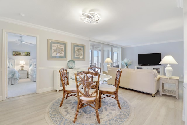 dining space featuring ceiling fan, light wood-style flooring, baseboards, and ornamental molding