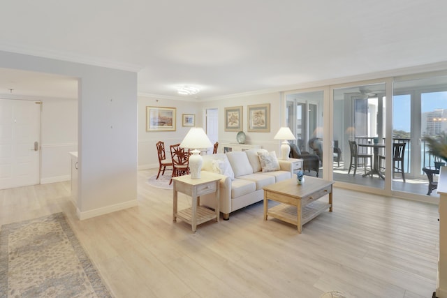 living area featuring baseboards, crown molding, and light wood finished floors