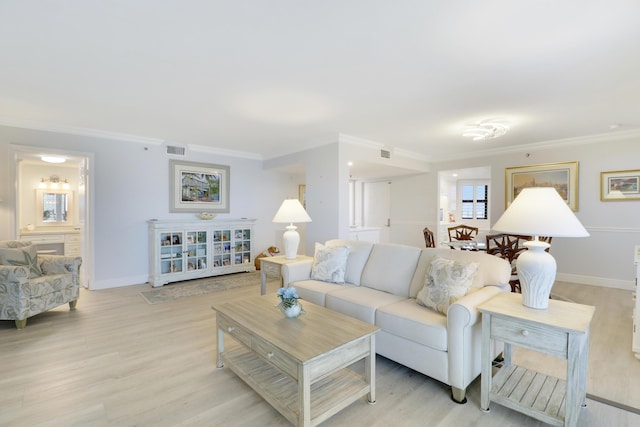 living area featuring crown molding, baseboards, visible vents, and light wood finished floors