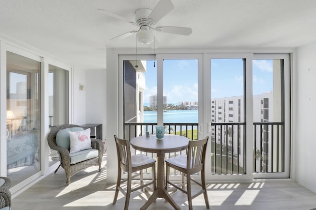 sunroom / solarium with plenty of natural light, ceiling fan, a view of city, and a water view