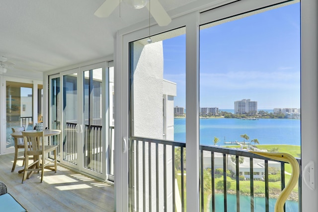 unfurnished sunroom featuring a water view, a city view, and ceiling fan