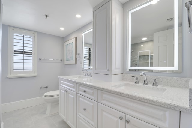 full bath featuring toilet, tiled shower, visible vents, and a sink