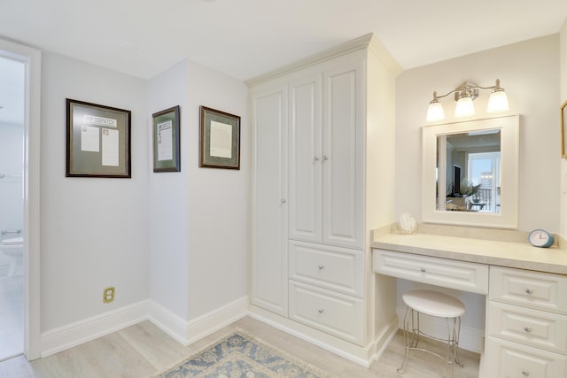 bathroom featuring toilet, vanity, baseboards, and wood finished floors