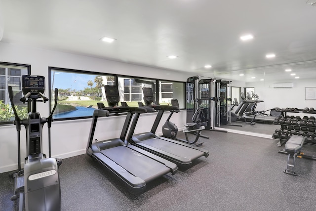 exercise room with recessed lighting, a wall mounted air conditioner, and baseboards