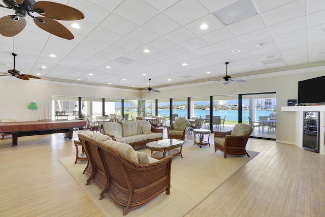 living room featuring ceiling fan, beverage cooler, light wood-type flooring, ornamental molding, and billiards