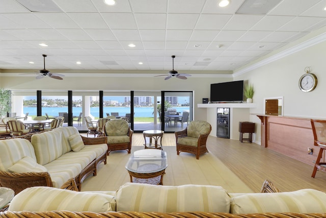 living room with a wealth of natural light, a ceiling fan, and ornamental molding