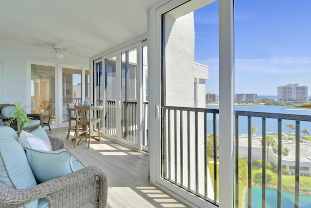 sunroom with a view of city, ceiling fan, and a water view