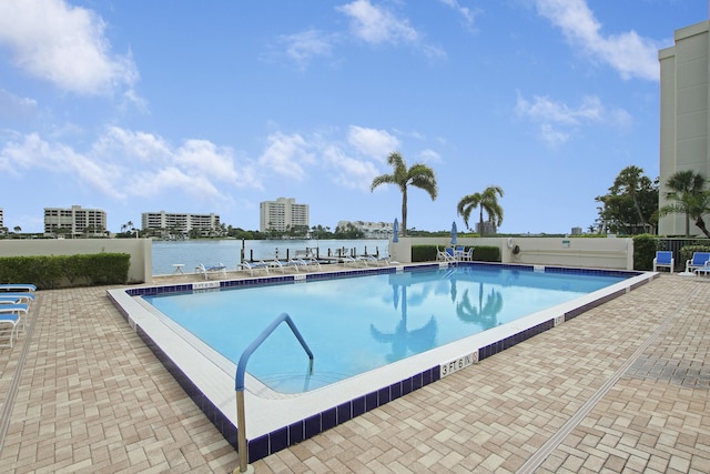 pool with a patio area, a city view, and a water view