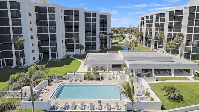 community pool with fence, a patio area, and a lawn