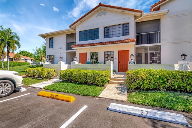 view of front of house featuring stucco siding, uncovered parking, and a tiled roof