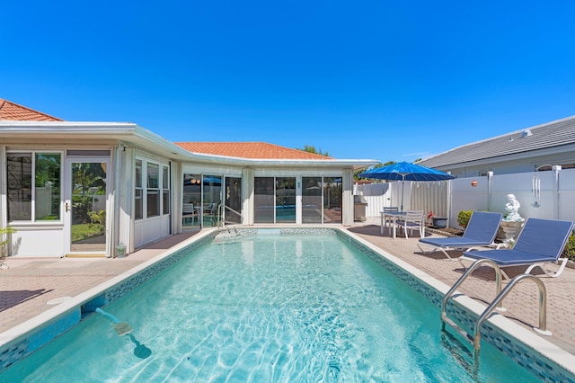 view of pool featuring a patio, fence, a fenced in pool, and a sunroom