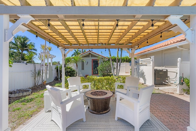 view of patio with an outbuilding, a fire pit, a fenced backyard, and a pergola