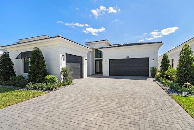 view of front of home featuring stucco siding, decorative driveway, and a garage