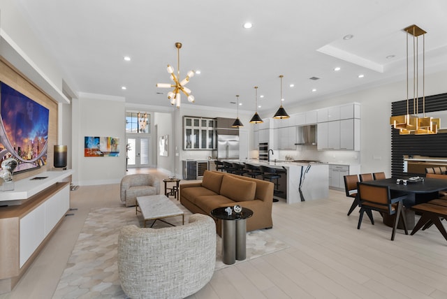 living room featuring light wood finished floors, a notable chandelier, recessed lighting, and crown molding