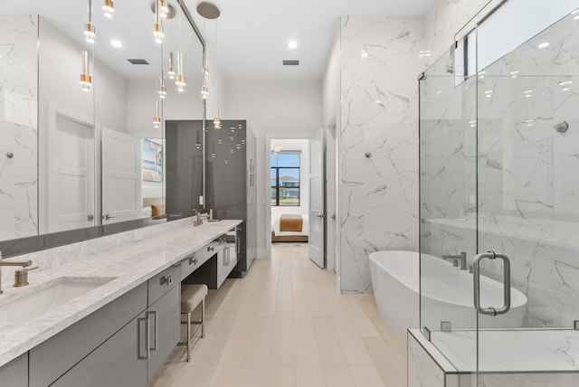 bathroom with ensuite bath, double vanity, a freestanding tub, a sink, and a shower stall