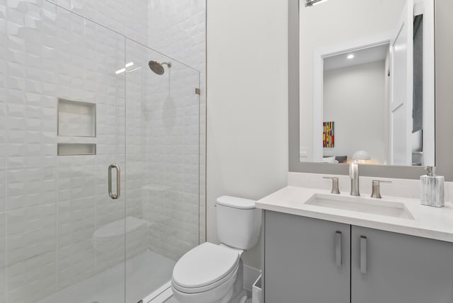 full bathroom featuring vanity, a shower stall, and toilet